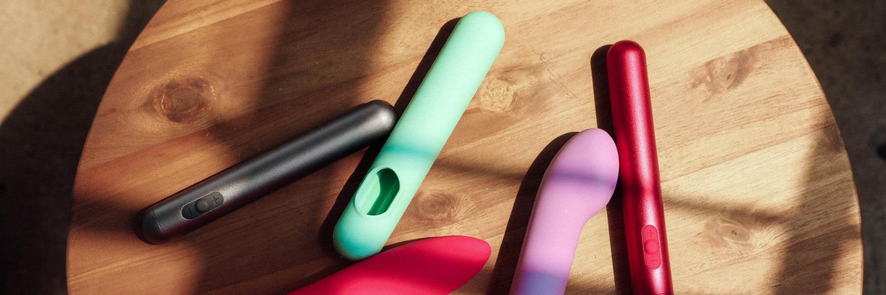 Colorful JIMMYJANE luxury wellness devices on a wooden table in natural light