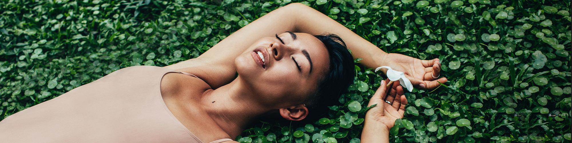 Relaxed woman lying on green leaves, holding a white luxury item by JIMMYJANE