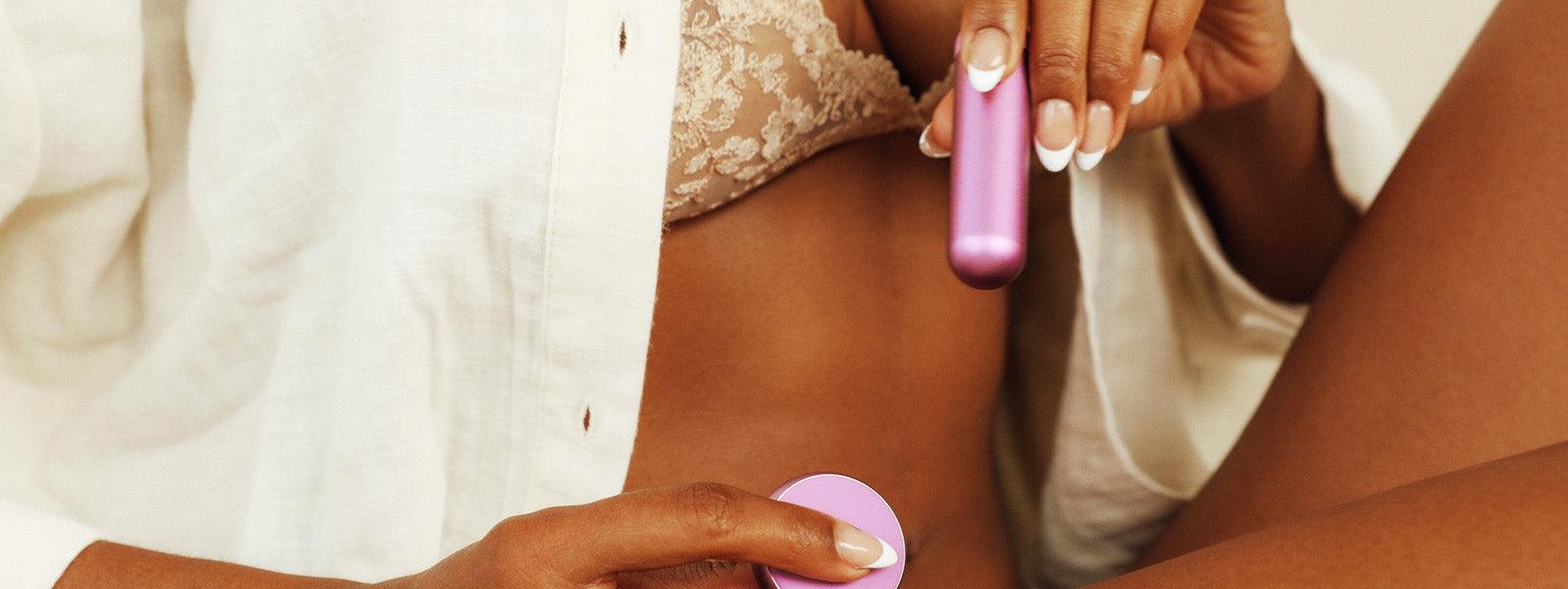Woman in lace lingerie and robe holding a pink JimmyJane luxury personal massager