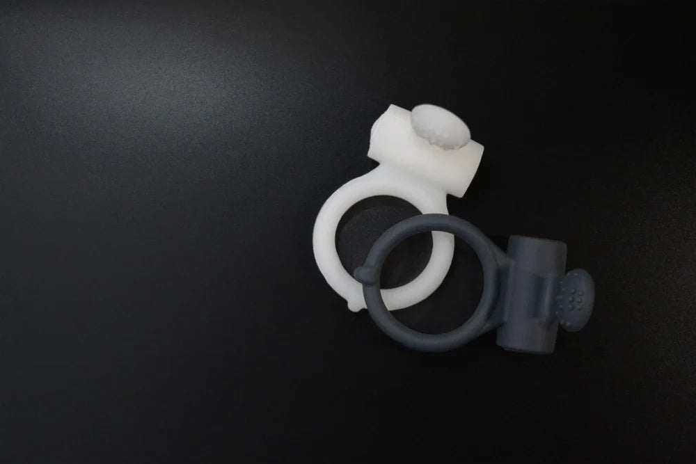 A black and white cock ring on a dark background.