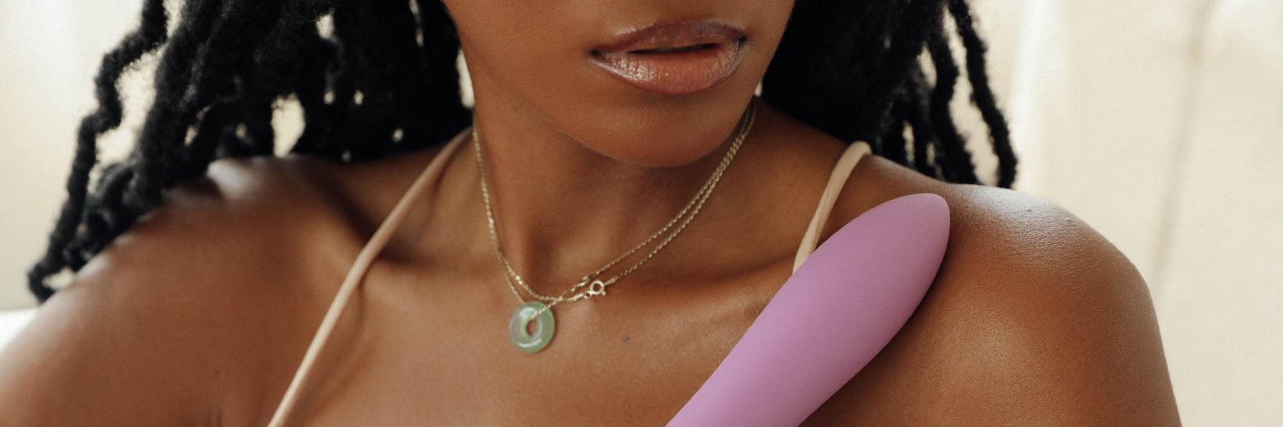 Woman with necklace holding premium pink personal massager on shoulder, JIMMYJANE luxury