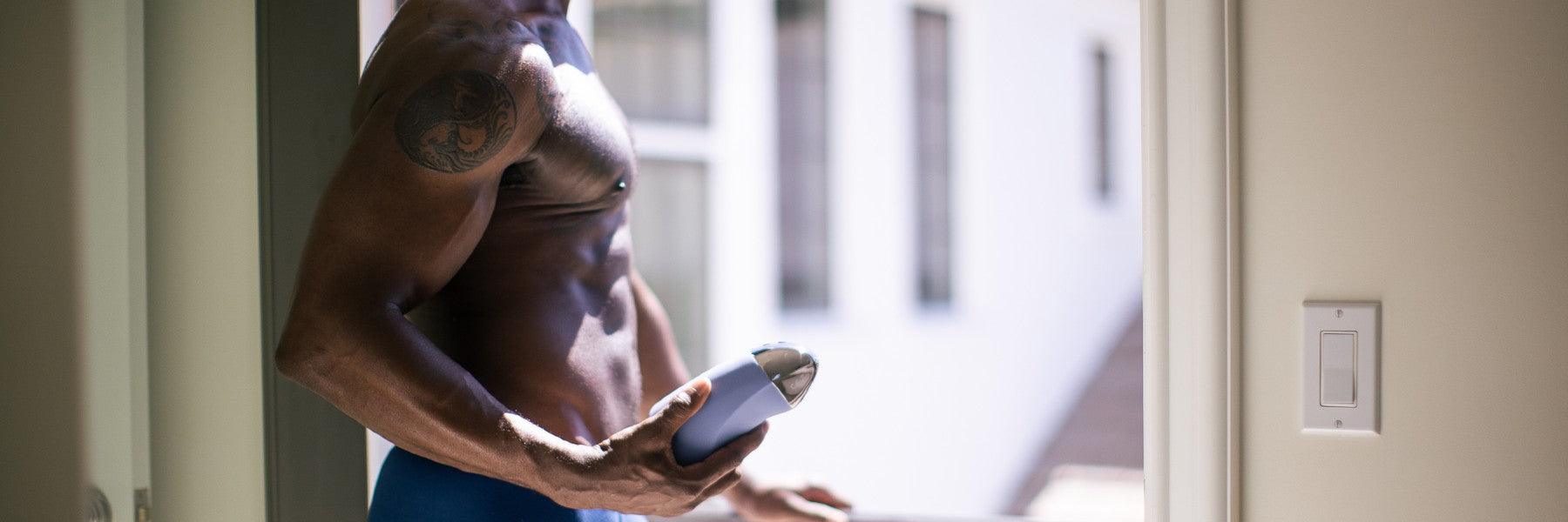 Fit man holding a modern luxury device indoors, Jimmyjane premium wellness brand