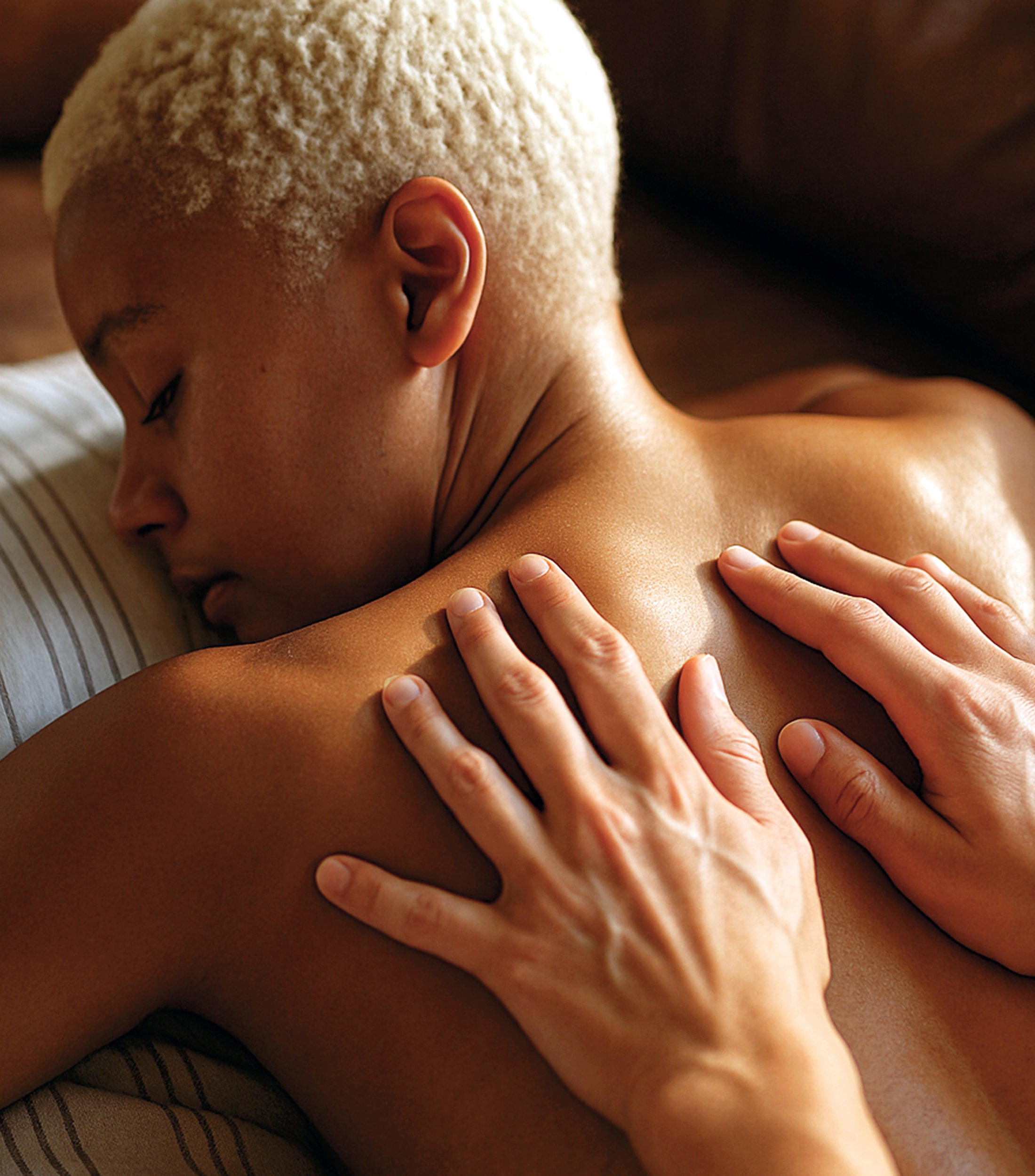 Person receiving a massage with hands on their shoulders and back.