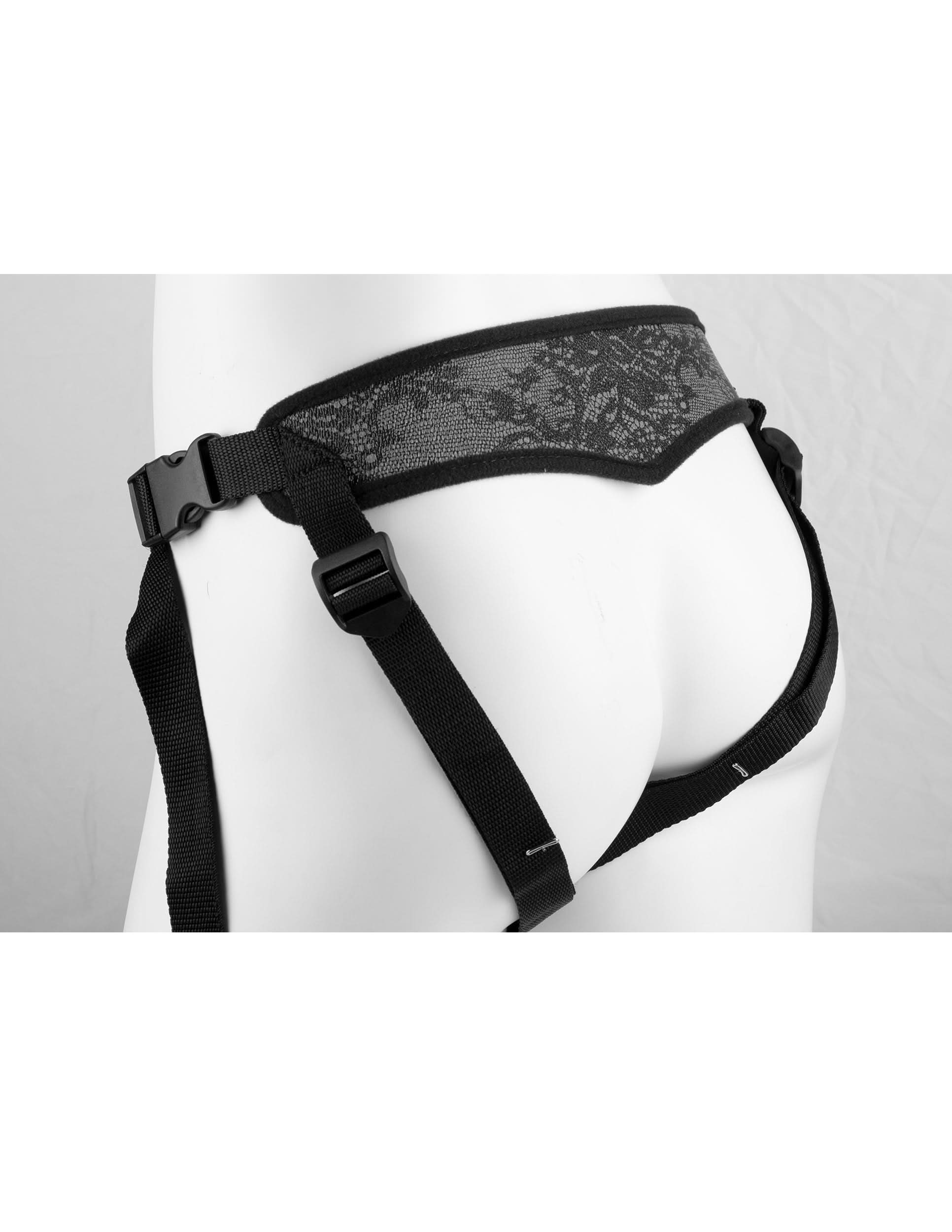 A person modeling the Dillio® Platinum Body Dock SE, a black harness system with lace details, buckles, and adjustable straps on their hips and thighs.