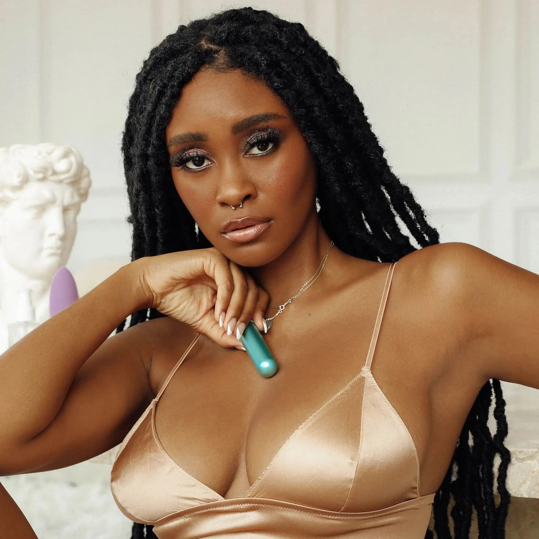 Woman in satin lingerie holding teal luxury adult wellness product by JIMMYJANE