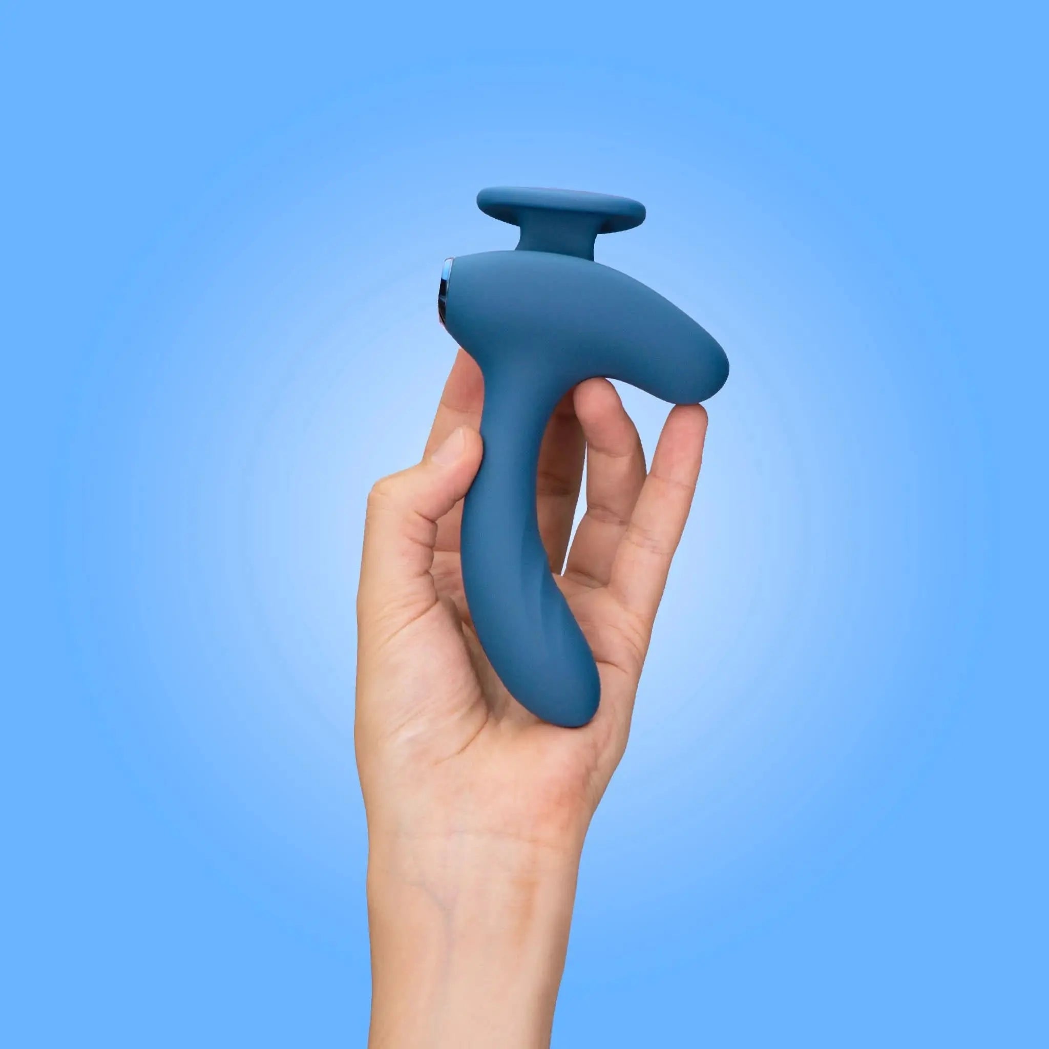Hand holding blue luxury JIMMYJANE® personal massager against light blue background