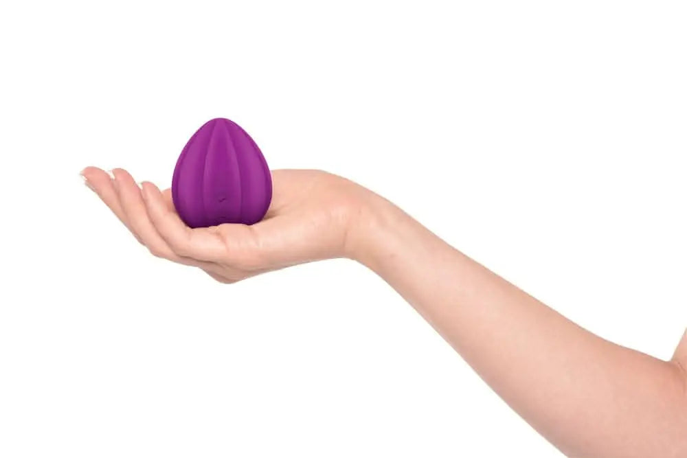 Purple JIMMYJANE luxury wellness massager resting on an open palm against white background