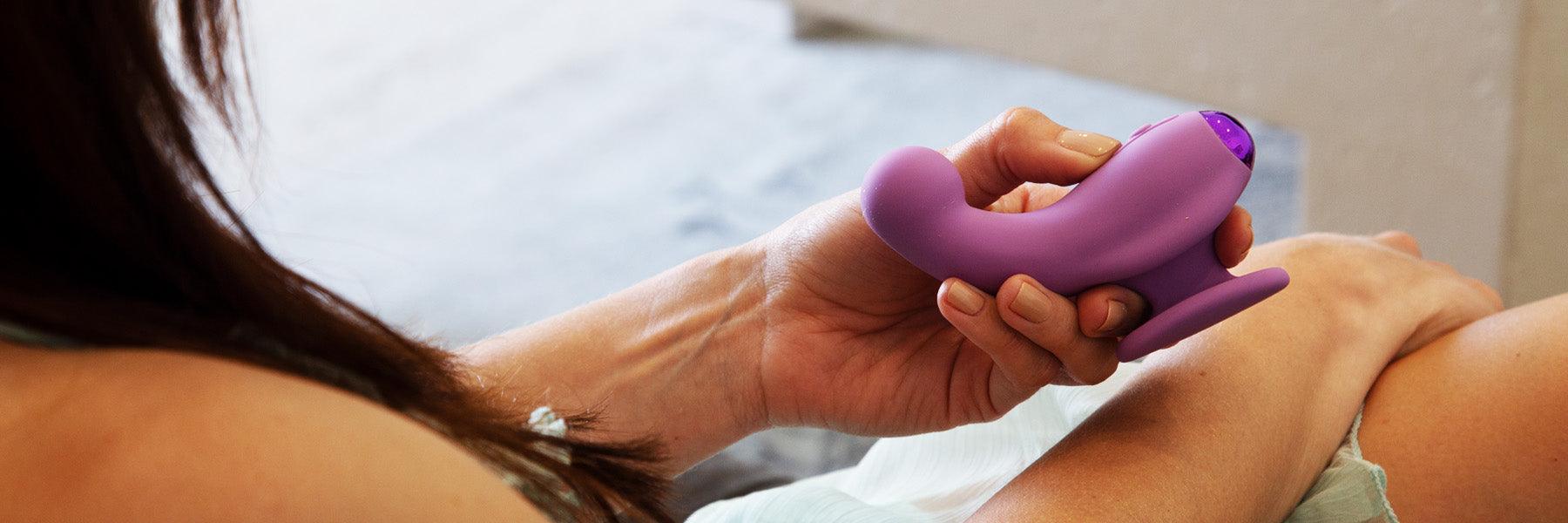 Woman holding a purple luxury personal massager by JIMMYJANE on bed