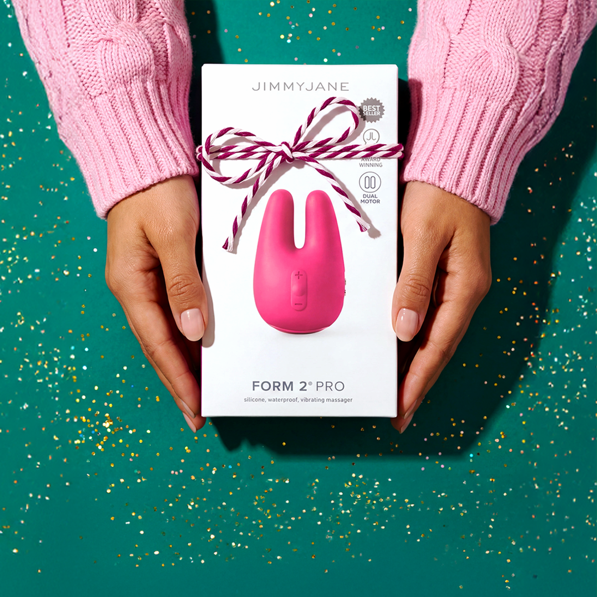 Pink 'Form 2 Pro' product packaging held by hands against a teal background with gold confetti.