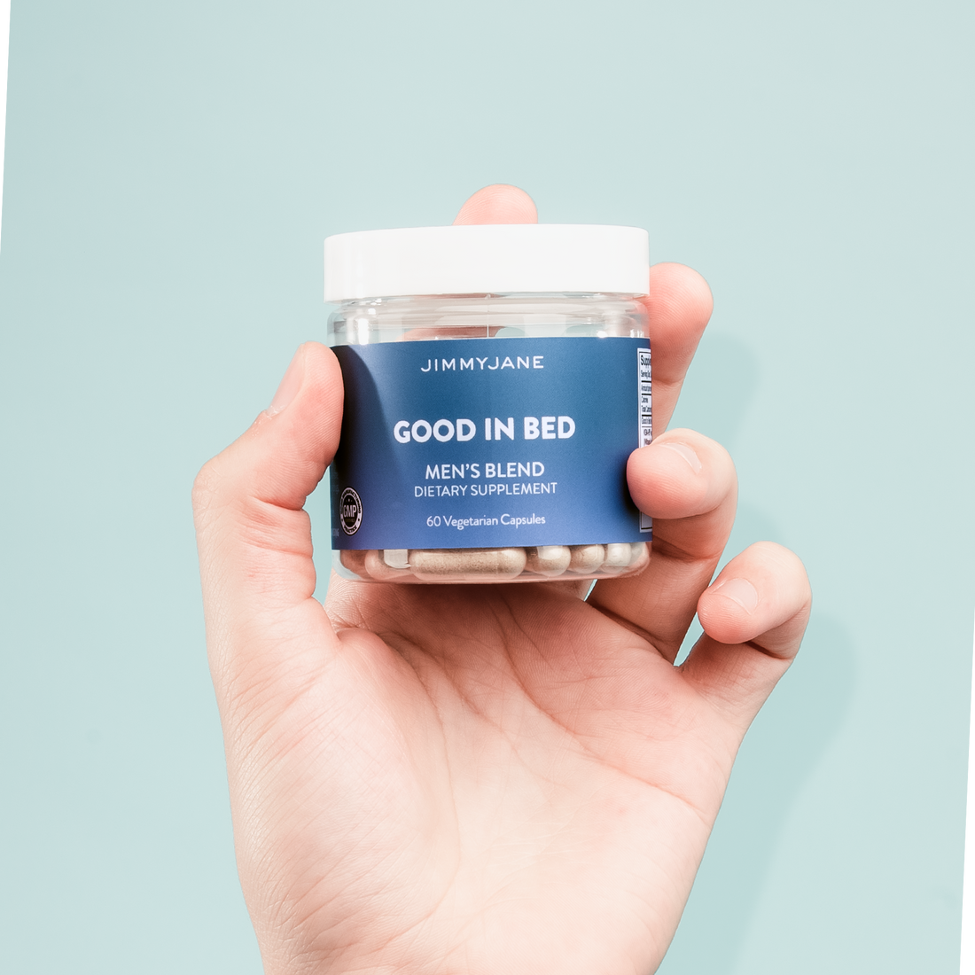 Jar of Good In Bed Men's Blend Dietary Supplements on blue background in a man's hand