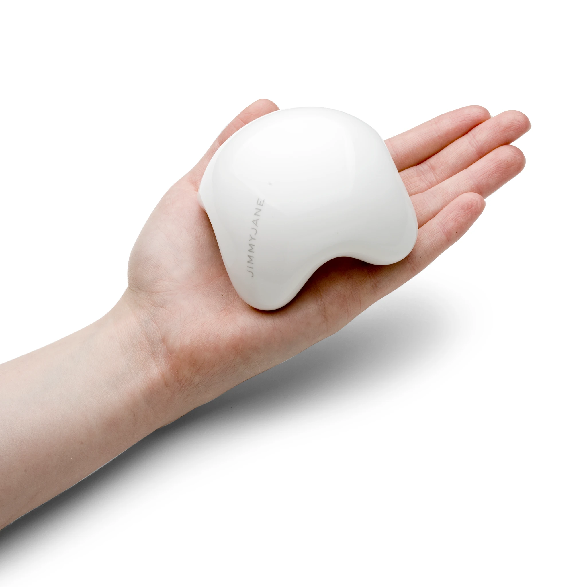 A hand holds the JIMMYJANE® Contour White Ceramic Massage Stone against a white background, highlighting its smooth, ergonomic design perfect for a luxurious full-body massage.