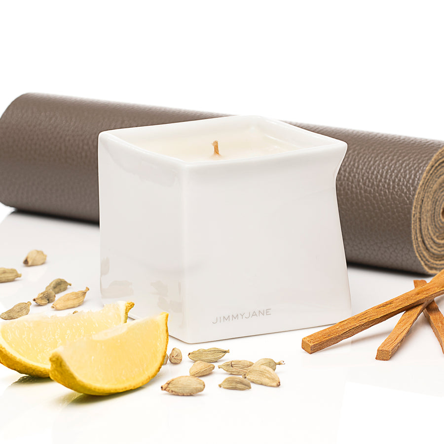 Santal scented Afterglow massage oil candle sitting on table surrounded by ingredients