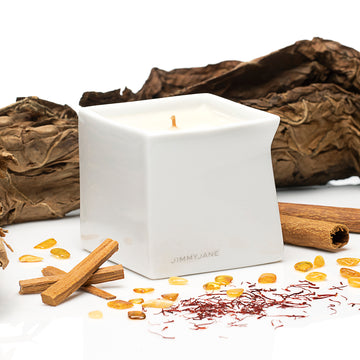 Red Tobacco scented Afterglow massage oil candle sitting on table surrounded by ingredients