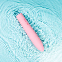 Self + Jimmyjane vibrating slimline massager in light pink laying in rippling water