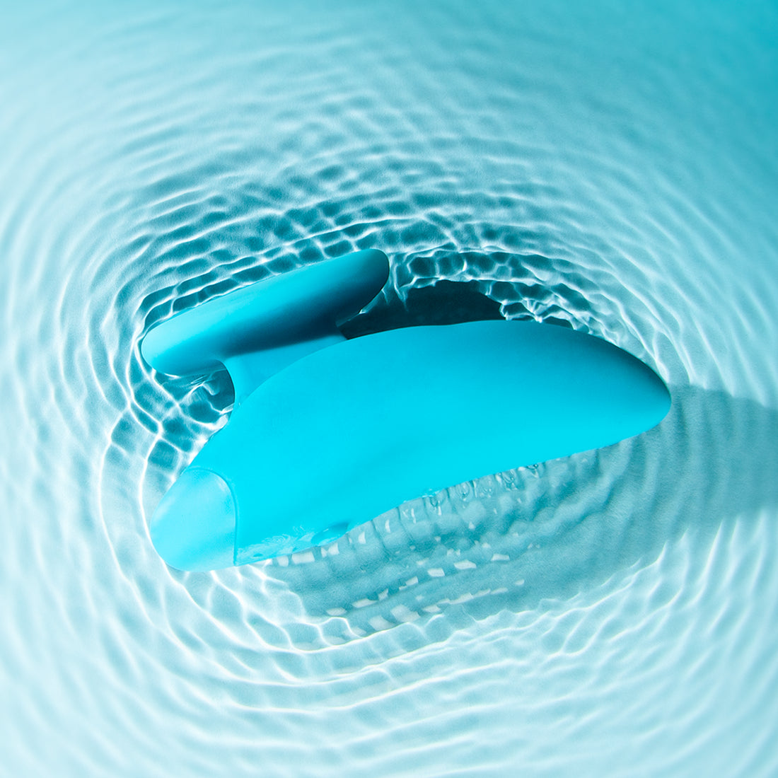 Self + Jimmyjane vibrating massager with finger grip in light blue laying in rippling water