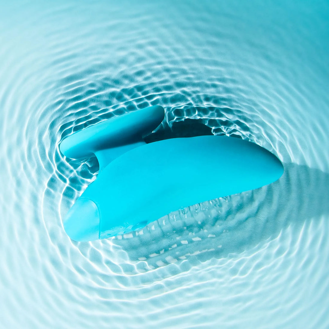 Self + Jimmyjane vibrating massager with finger grip in light blue laying in rippling water